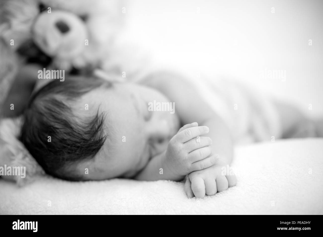 Cute newborn baby sleeps on a blanket with a toy teddy bear - happy family moments Stock Photo