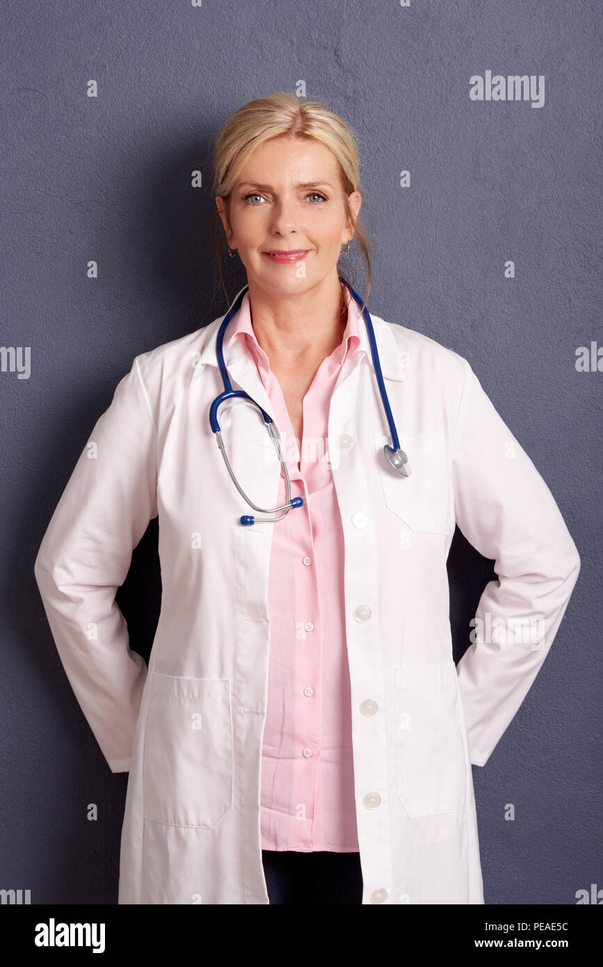 Portrait of beautiful mature female doctor standing at grey wall Stock ...