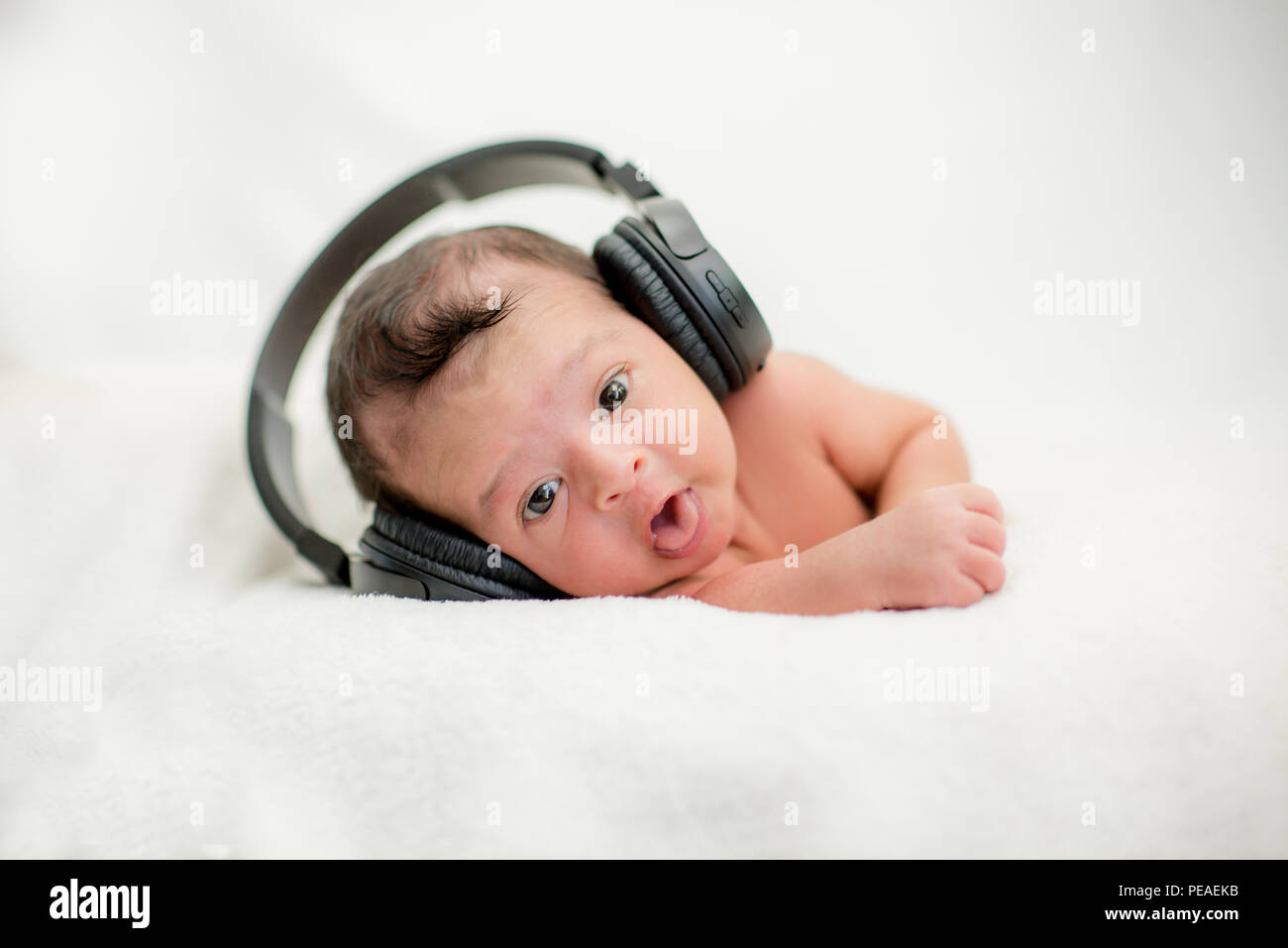 Cute newborn baby hearing music with headphones on a blanket happy