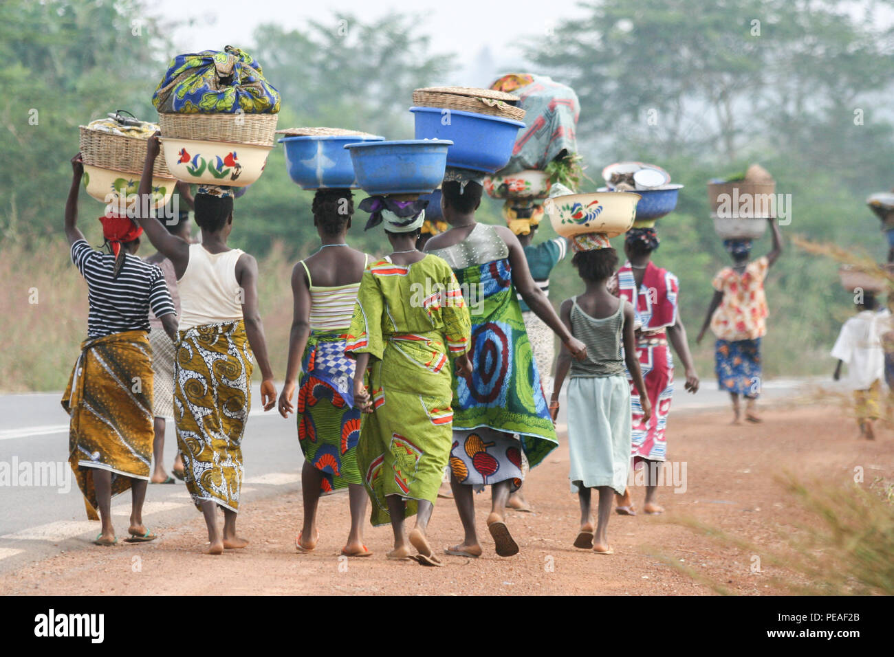 African women carrying bowls on their heads walking down the road in