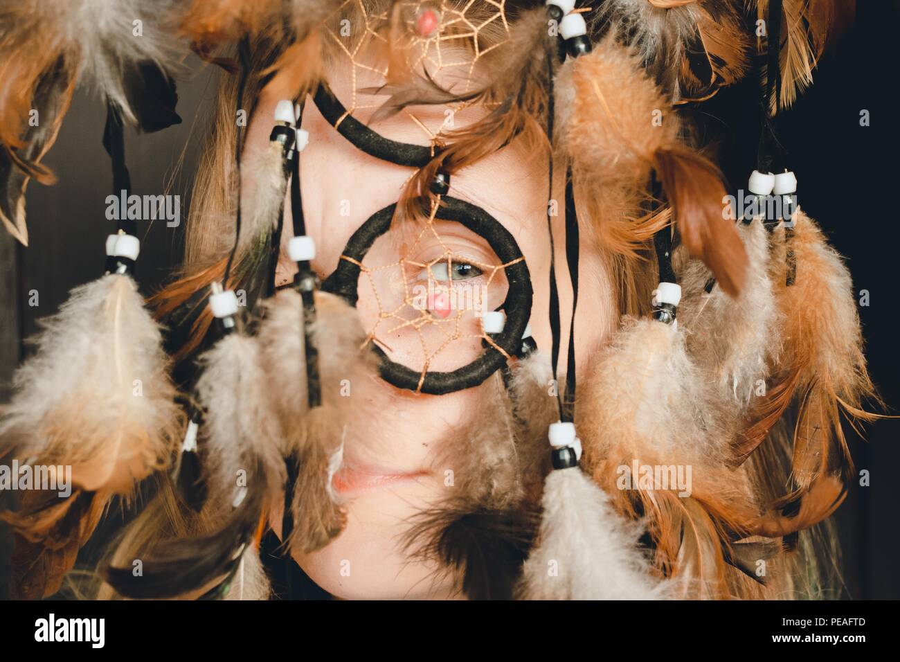 The girl looks through the ring of the dream catcher with one eye ...