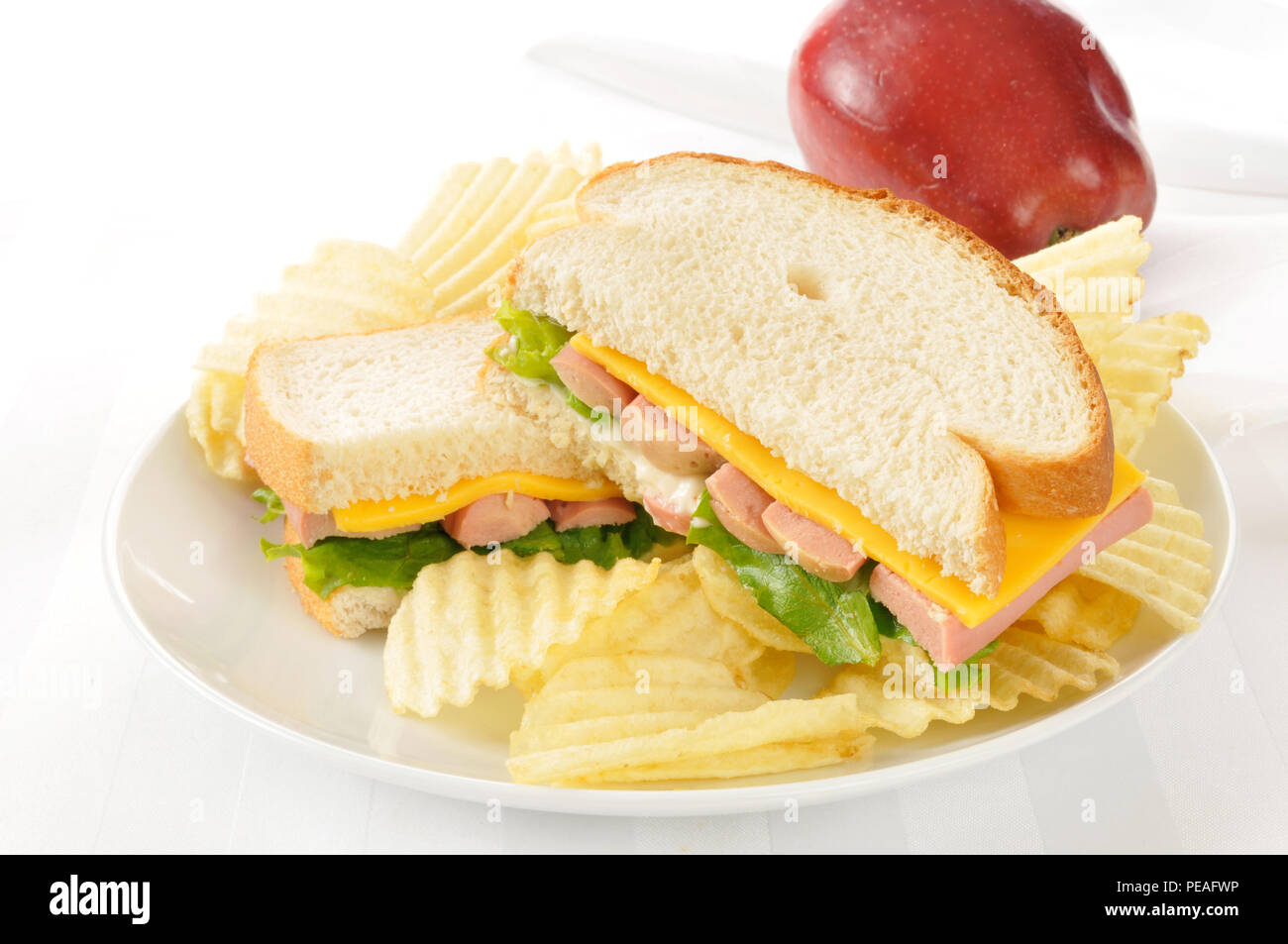 a vienna sausage and cheese sandwich with potato chips and an apple