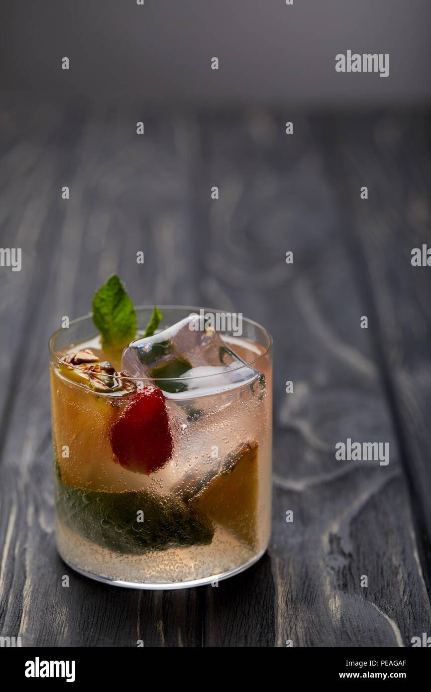 glass of lemonade with ice cubes, mint leaves, pineapple pieces and strawberry Stock Photo