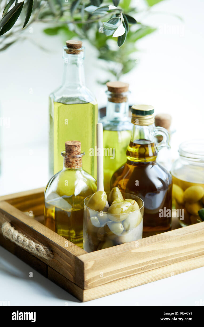 https://c8.alamy.com/comp/PEAGY8/glass-with-spoon-and-olives-jar-various-bottles-of-aromatic-olive-oil-with-and-branches-on-wooden-tray-PEAGY8.jpg