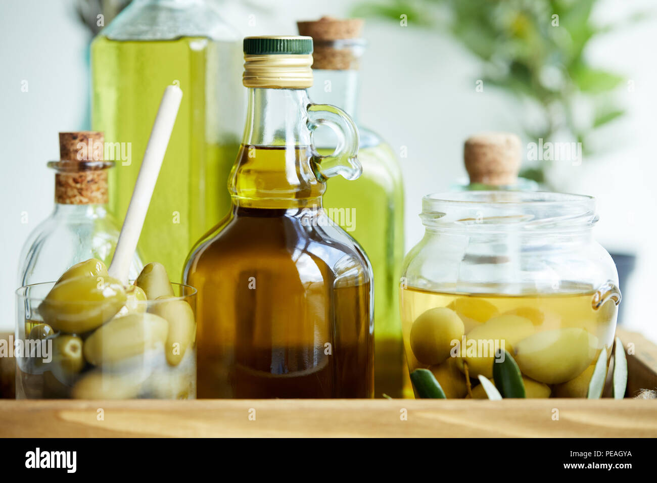 glass with spoon and green olives, jar, various bottles of aromatic