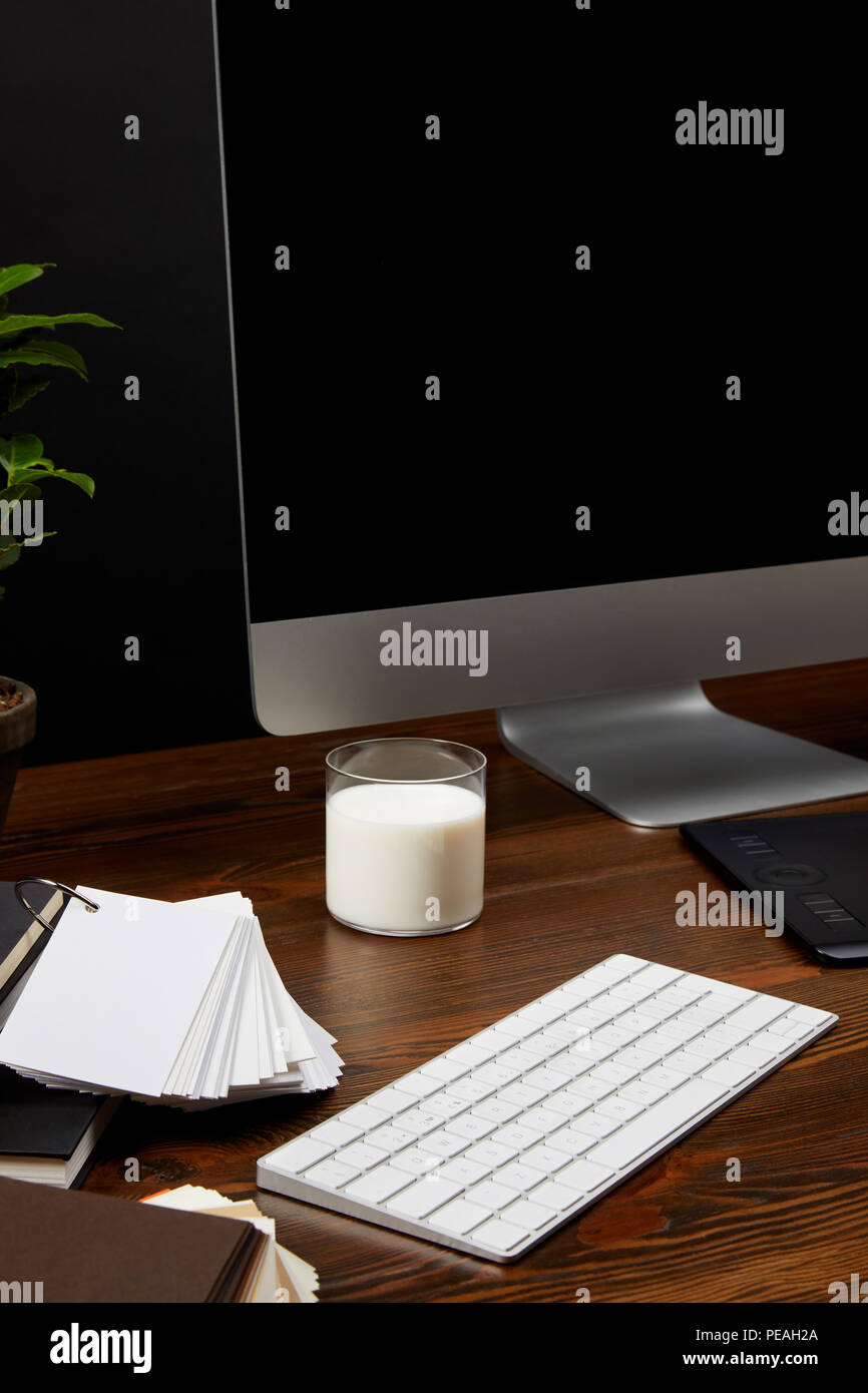 close up view of designer workplace with glass of milk, computer screen ...