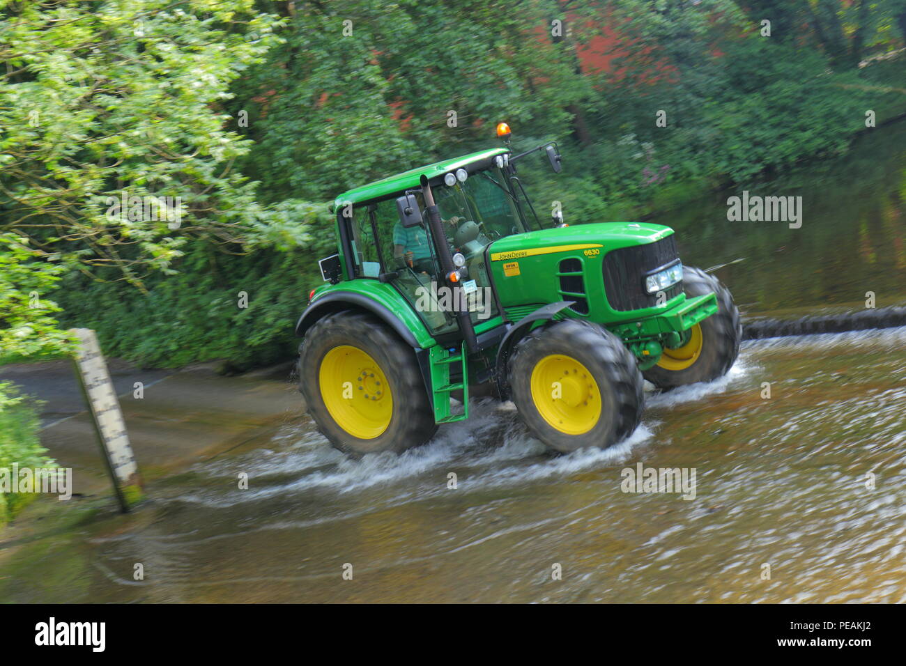 A John Deere Tractor crosses the River Skell in Ripon during a convoy