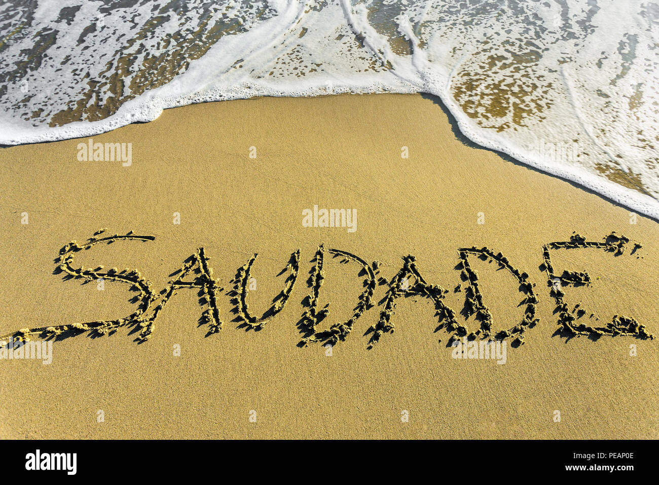 Saudade, Portuguese word meaning nostalgia or longing composed with yellow  colored stone letters over green sand Stock Photo - Alamy