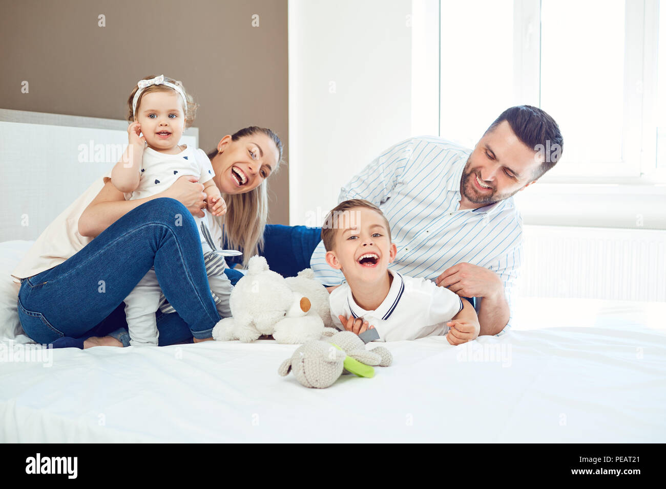 Happy family  playing lying on the bed in the bedroom. Stock Photo