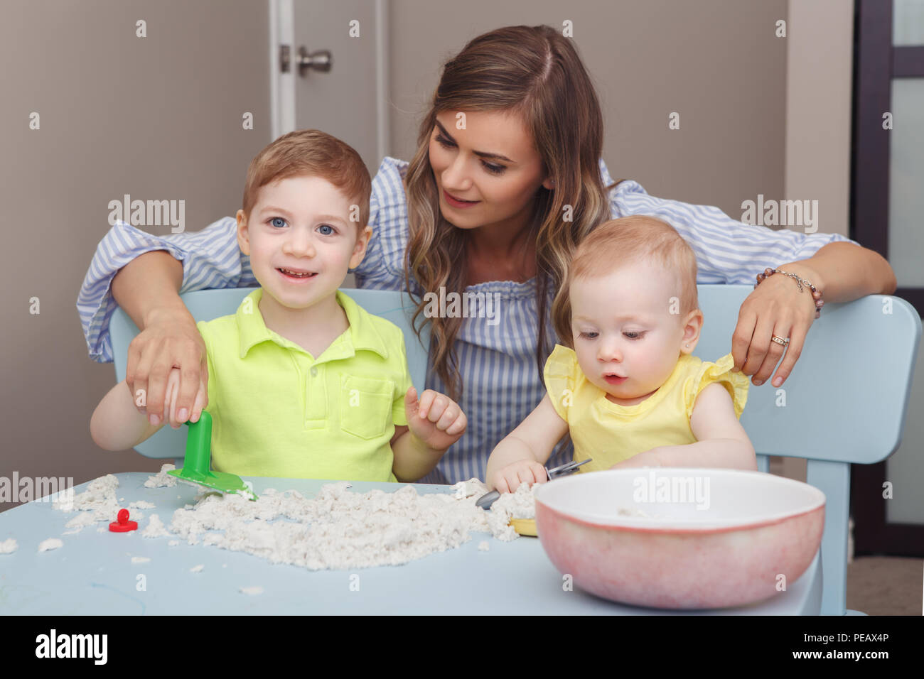 Group portrait of young white Caucasian mother with children playing kinetic sand together at home. Early creativity brain development concept. Lifest Stock Photo