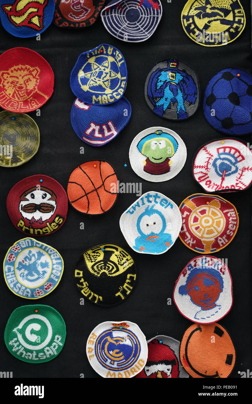A selection of Jewish kippahs (also called a kappel or skull cap) adapted to carry modern brands and sports names on a market stall in Machane Yehuda  Stock Photo
