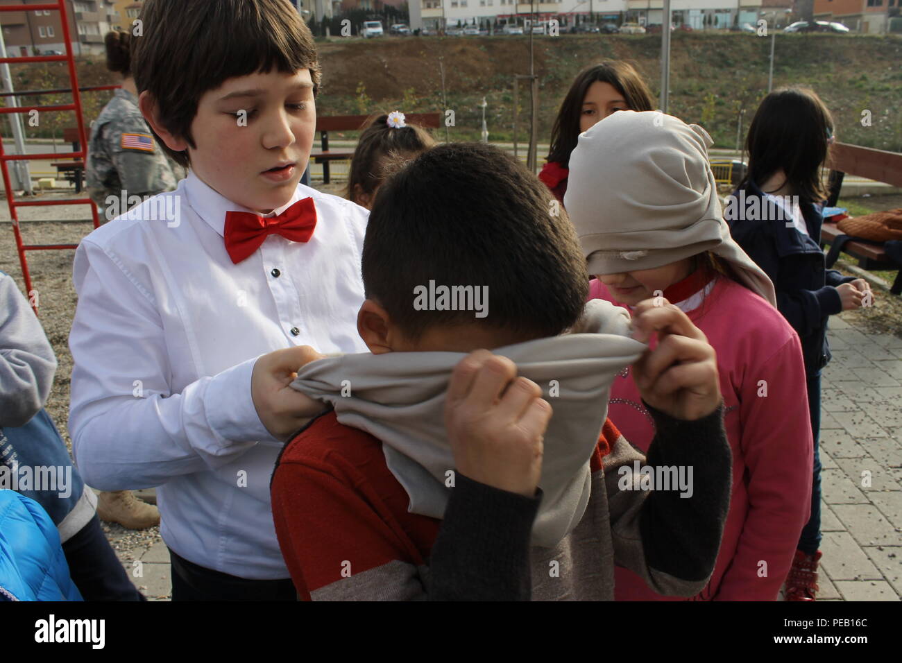 A&A Learning Center students wrap blindfolds on their classmates as they prepare to participate in a trust-building exercises led by U.S. Soldiers assigned to Multinational Battle Group-East, who visited the school, Nov. 23, 2015, in Pristina, Kosovo. The Soldiers delivered donated school supplies and artwork painted by students from Saint Francis de Sales Catholic School, in Beckley, W.Va., to the learning center as part of a community outreach mission that included practicing language skills and joining the children on a trip to Pristina’s Bear Sanctuary. (U.S. Army photo by Sgt. Erick Yates Stock Photo