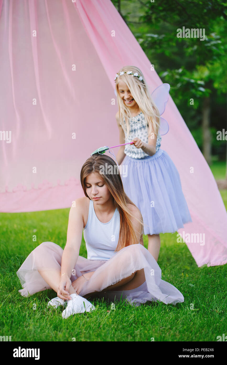 Portrait of two smiling funny Caucasian girls sisters wearing pink tutu