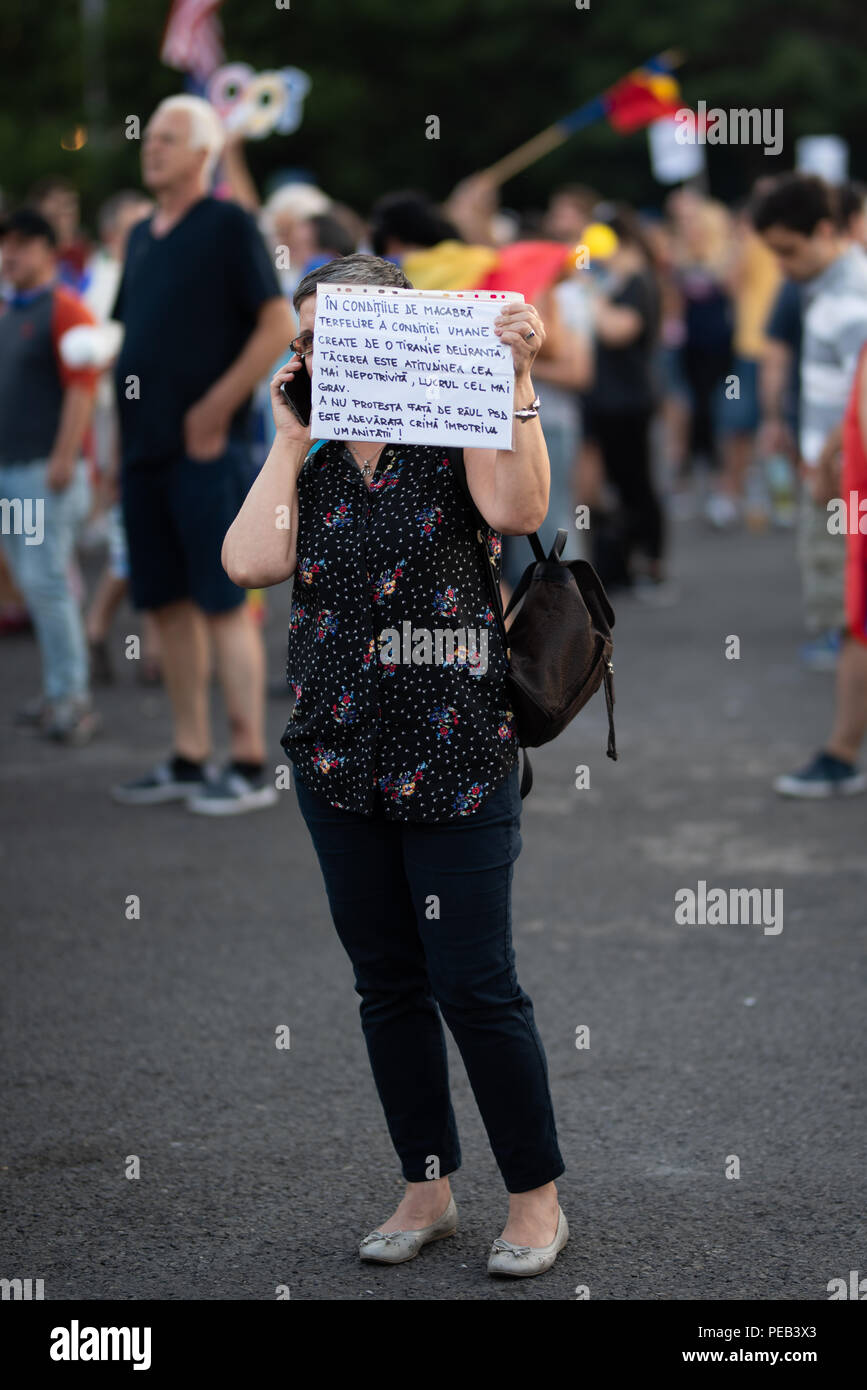 Romania, Bucharest - August 12, 2018: Protester holding sign while talking on the phone Stock Photo