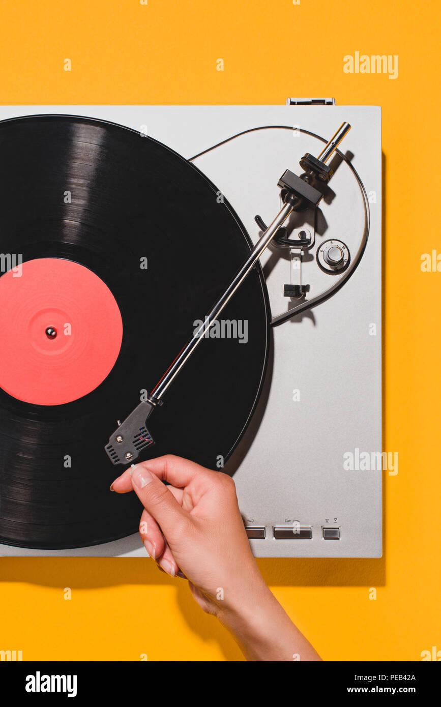 cropped shot of woman turning on vinyl player isolated on yellow Stock Photo