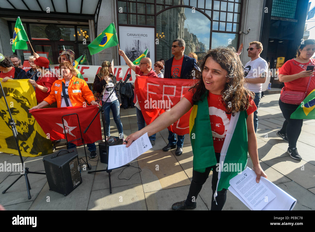 London, UK. 13th August 2018.  A woman hands out flyers as Brazilians protest outside the Brazilian embassy calling for the release of Luiz Inacio Lula da Silva, a former trade union leader who was President of Brazil from 2003-11 to enable him to stand for election again in October. Credit: Peter Marshall/Alamy Live News Stock Photo