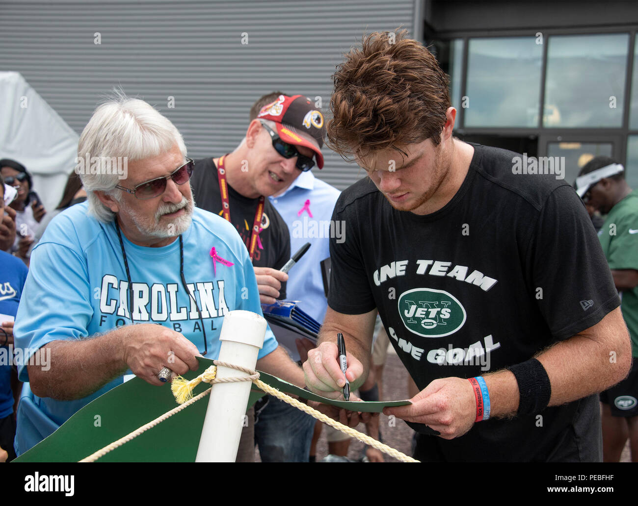 Landover, United States Of America. 13th Aug, 2018. New York Jets  quarterback Sam Darnold (14), right, signs an autograph for an unidentified  fan after participating in a joint training camp practice with