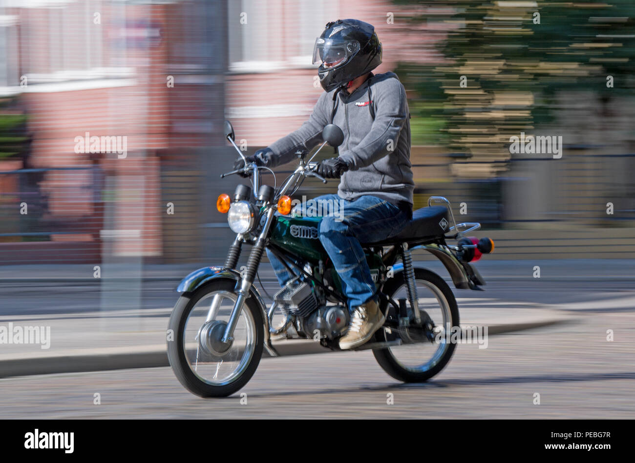 25 July 2018, Germany, Halle/Saale: Marco Rauchhaupt, driving instructor  from Halle, drives through the native town of Haendel on a Simson S51. The  cult scooter serves as a training vehicle in the