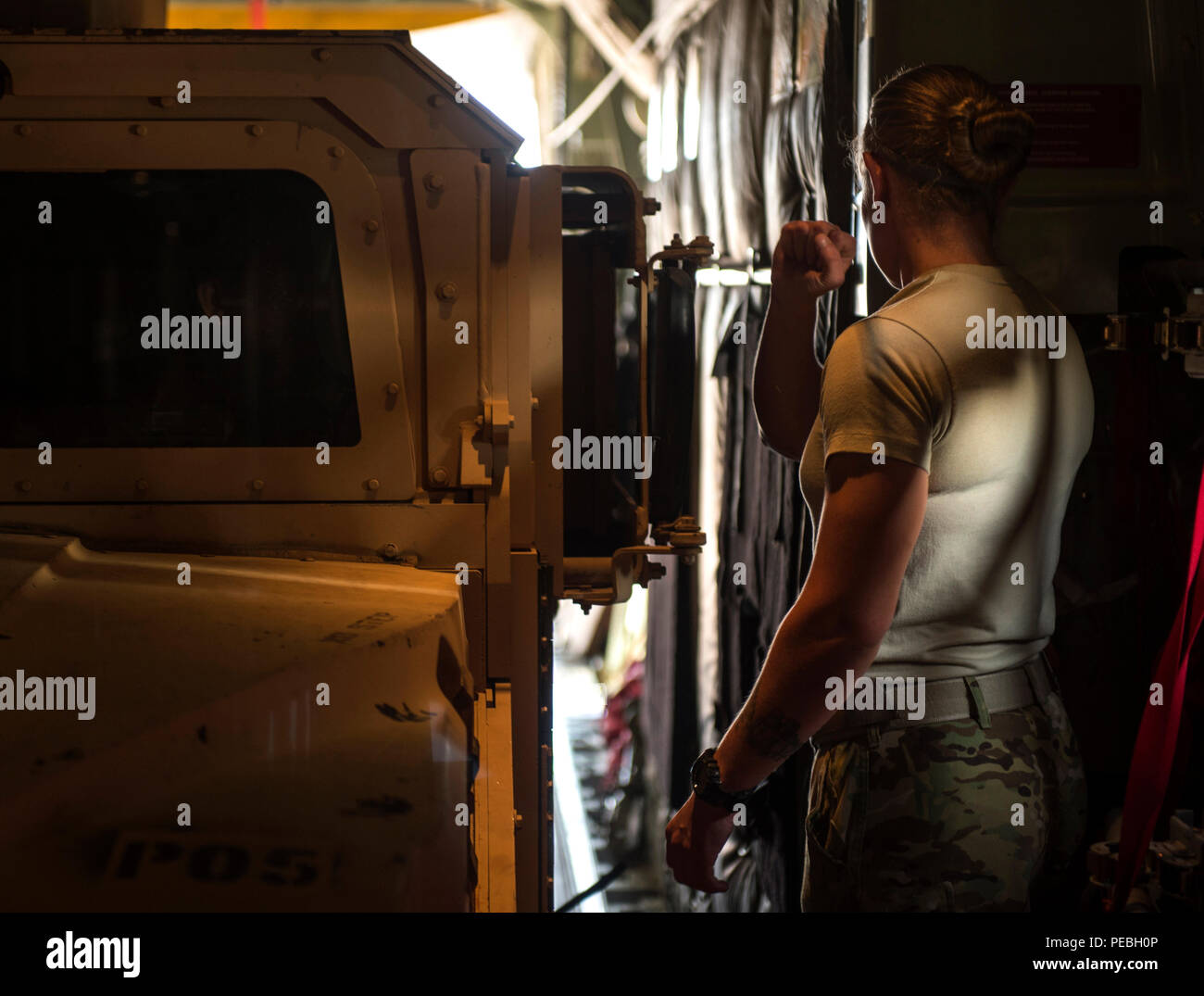 Staff Sgt. Whitney Woolverson, 75th Expeditionary Airlift Squadron loadmaster, directs a Charlie Co. 2-124 up-armored Humvee into a C-130J Super Hercules, Nov. 24, 2015, at Camp Lemonnier, Djibouti. The vehicle and additional cargo were delivered to Task Force Seminole of the Florida Army National Guard, which is deployed to a forward operating location in support of the Combined Joint Task Force-Horn of Africa mission. (U.S. Air Force photo by Senior Airman Peter Thompson) Stock Photo