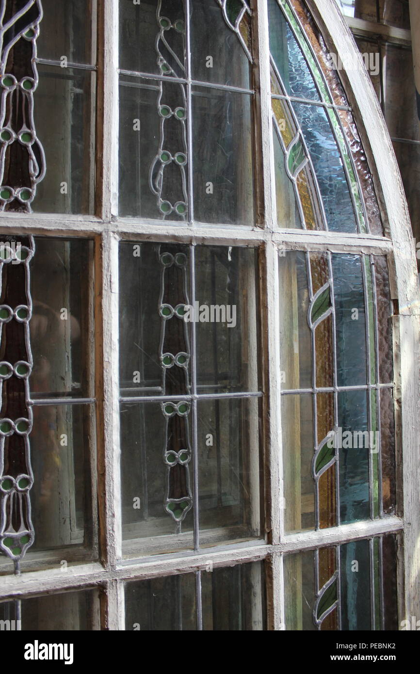 Arched stained glass window leaning against a wall at Architectural