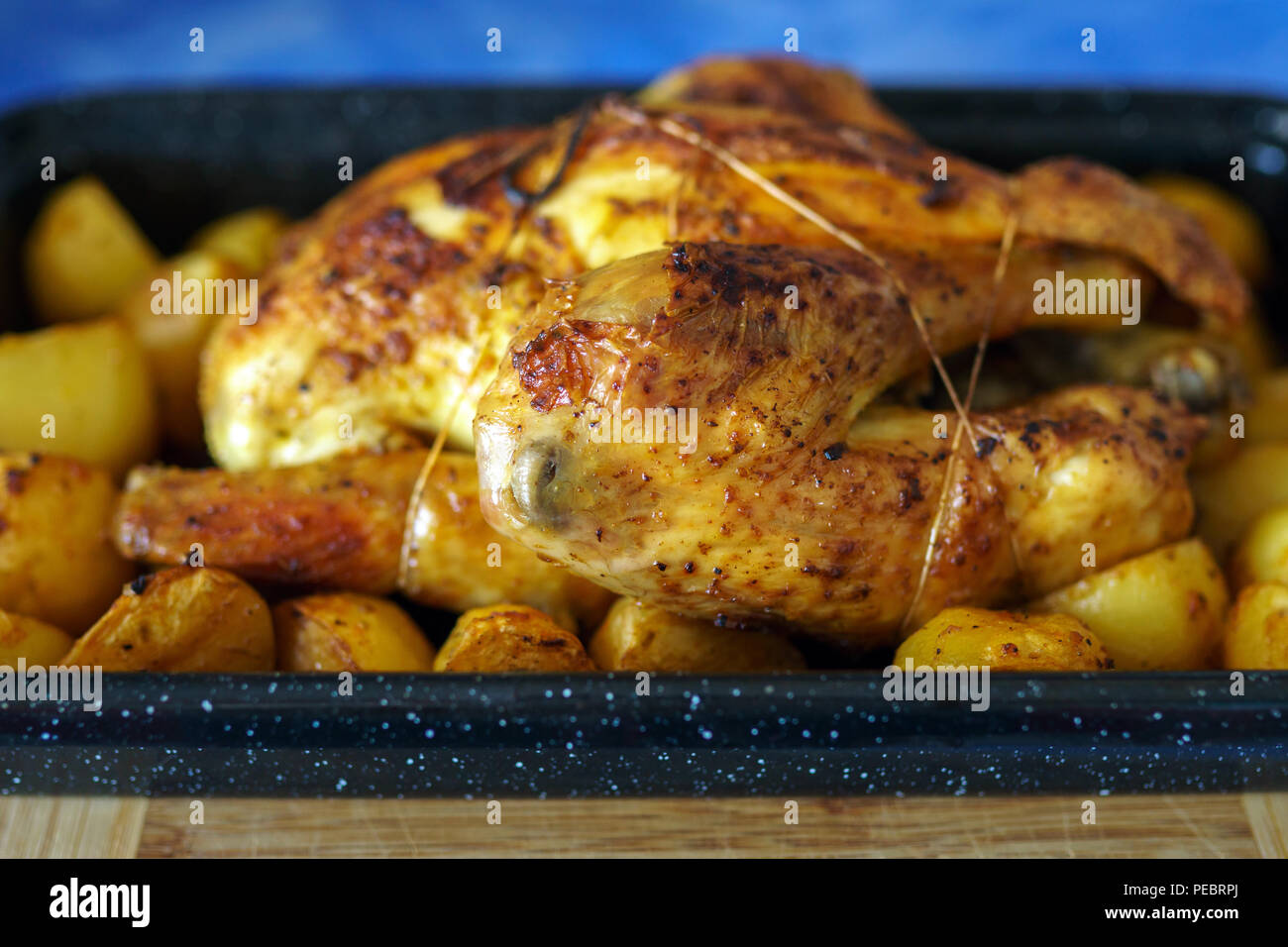 Whole chicken slow cooked in the oven with potatoes in the tray Stock