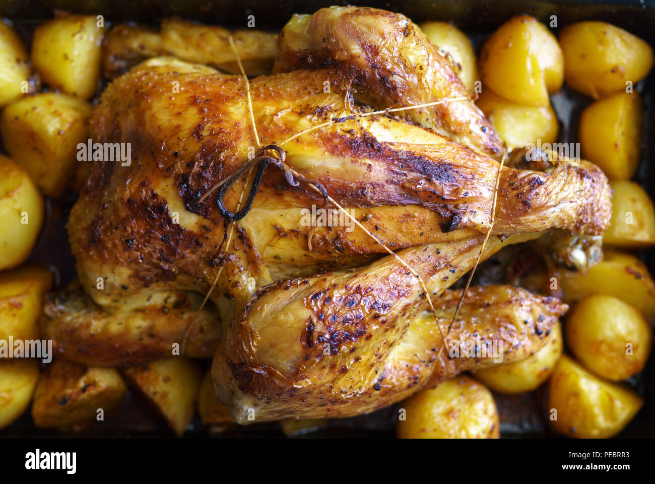 Whole chicken slow cooked in the oven with potatoes in the tray Stock