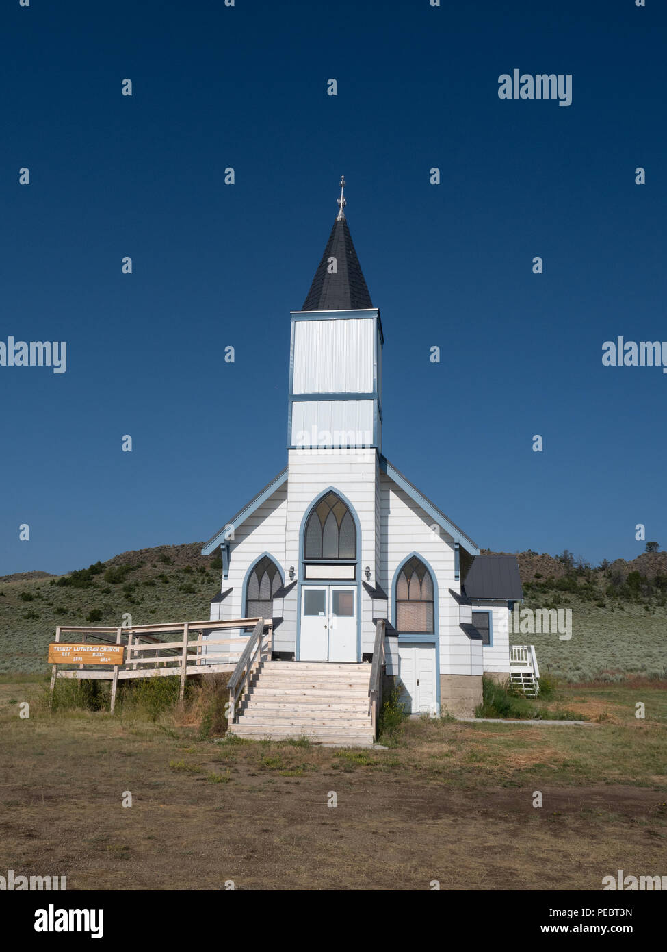 The old white clapboard Trinity Lutheran Church in Lennep Montana with hills, sage brush and blue sky in the background. Stock Photo