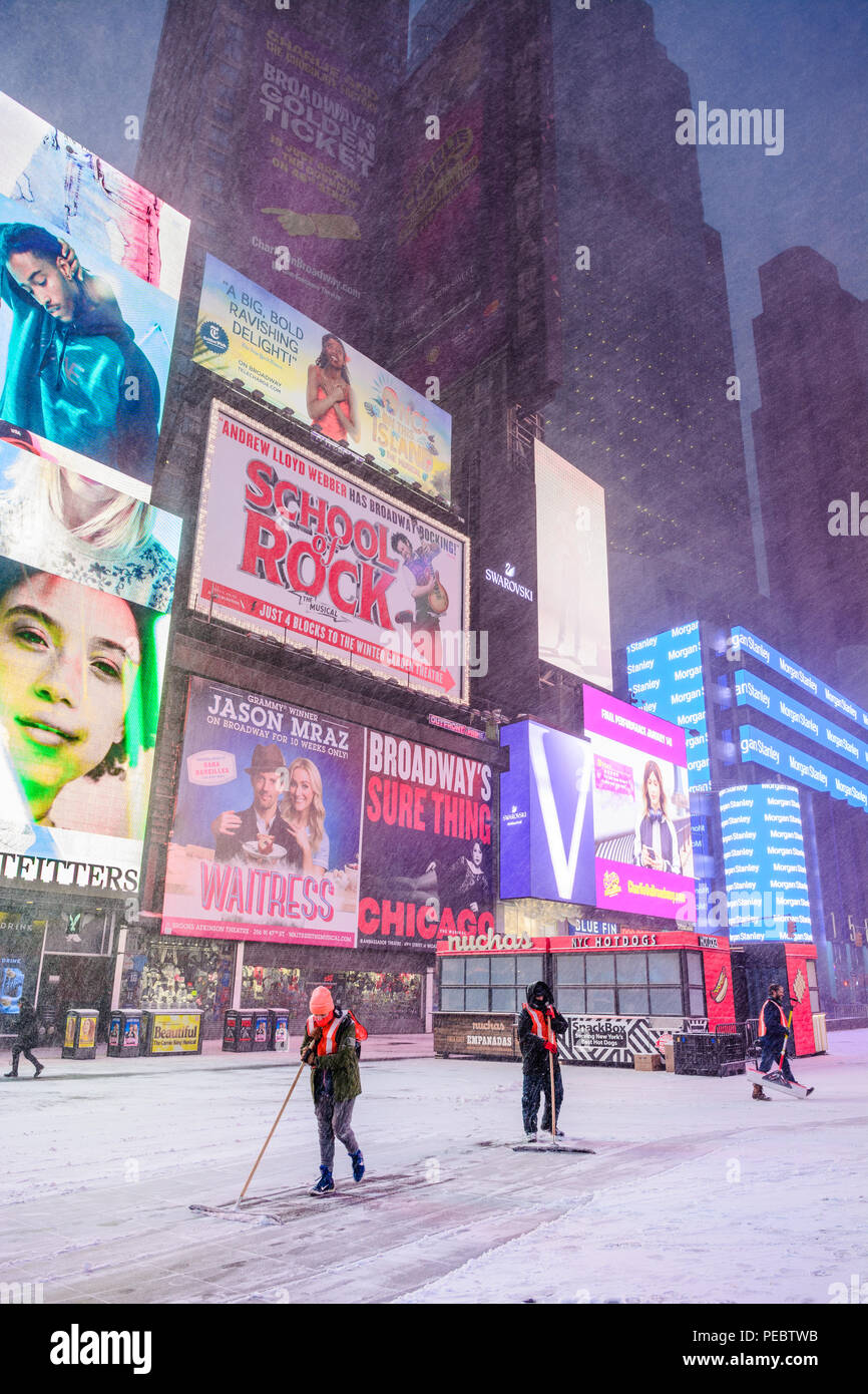 Times Square workers shoveling snow on the sidewalk during Winter Storm Grayson January 2018. Stock Photo