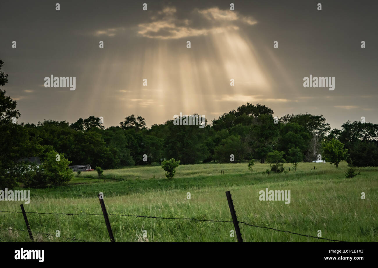 Rays Burst Through Storm Clouds Over Pasture Stock Photo