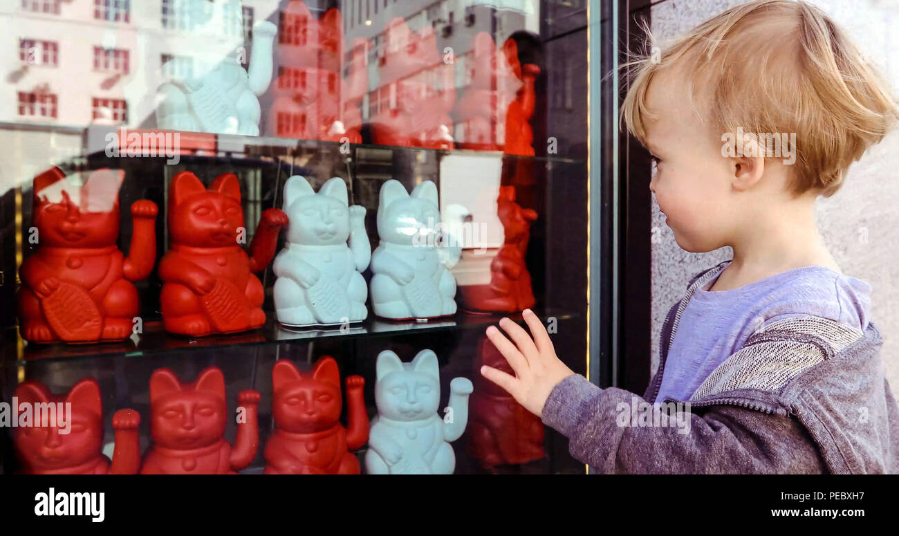 Baby boy waving hand while watching Maneki neko Stock Photo