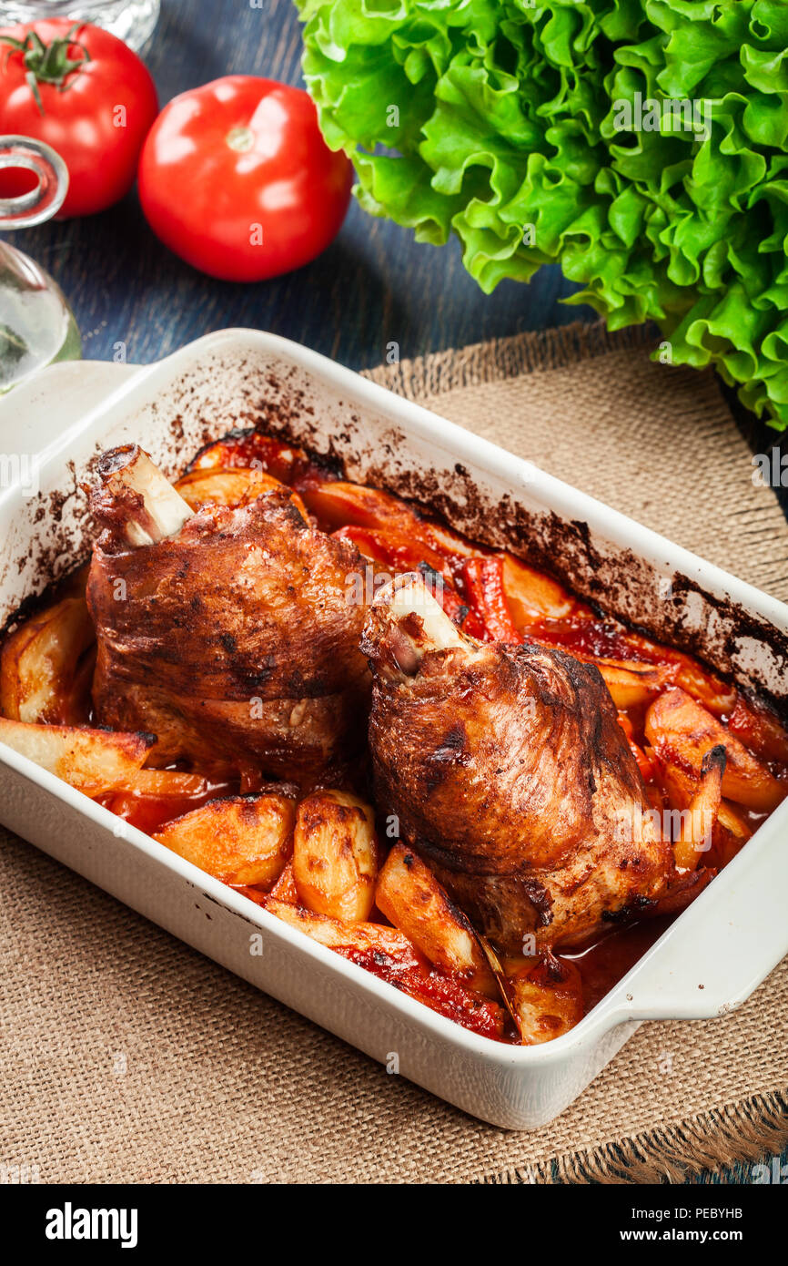 Roasted turkey knuckle with potatoes and vegetable in the baking dish