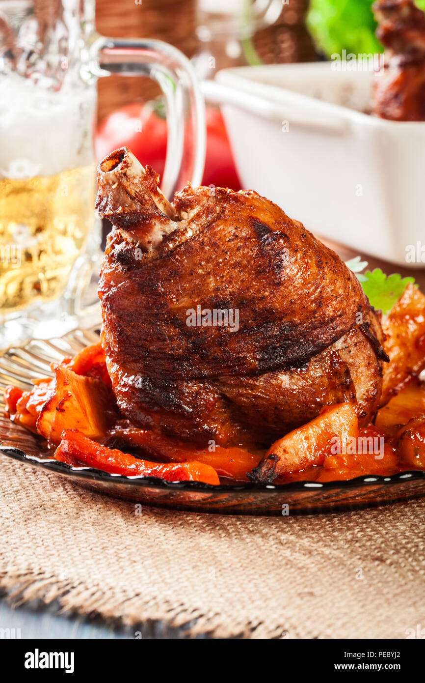 Roasted turkey knuckle with potatoes and vegetable on a plate Stock