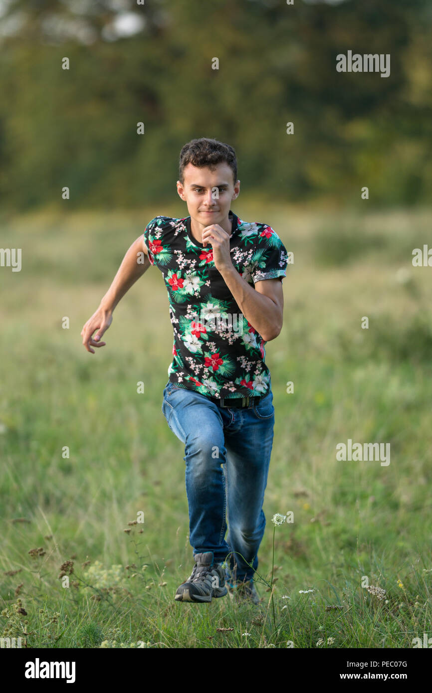Young boy running outdoor through the forest in the grass Stock Photo ...