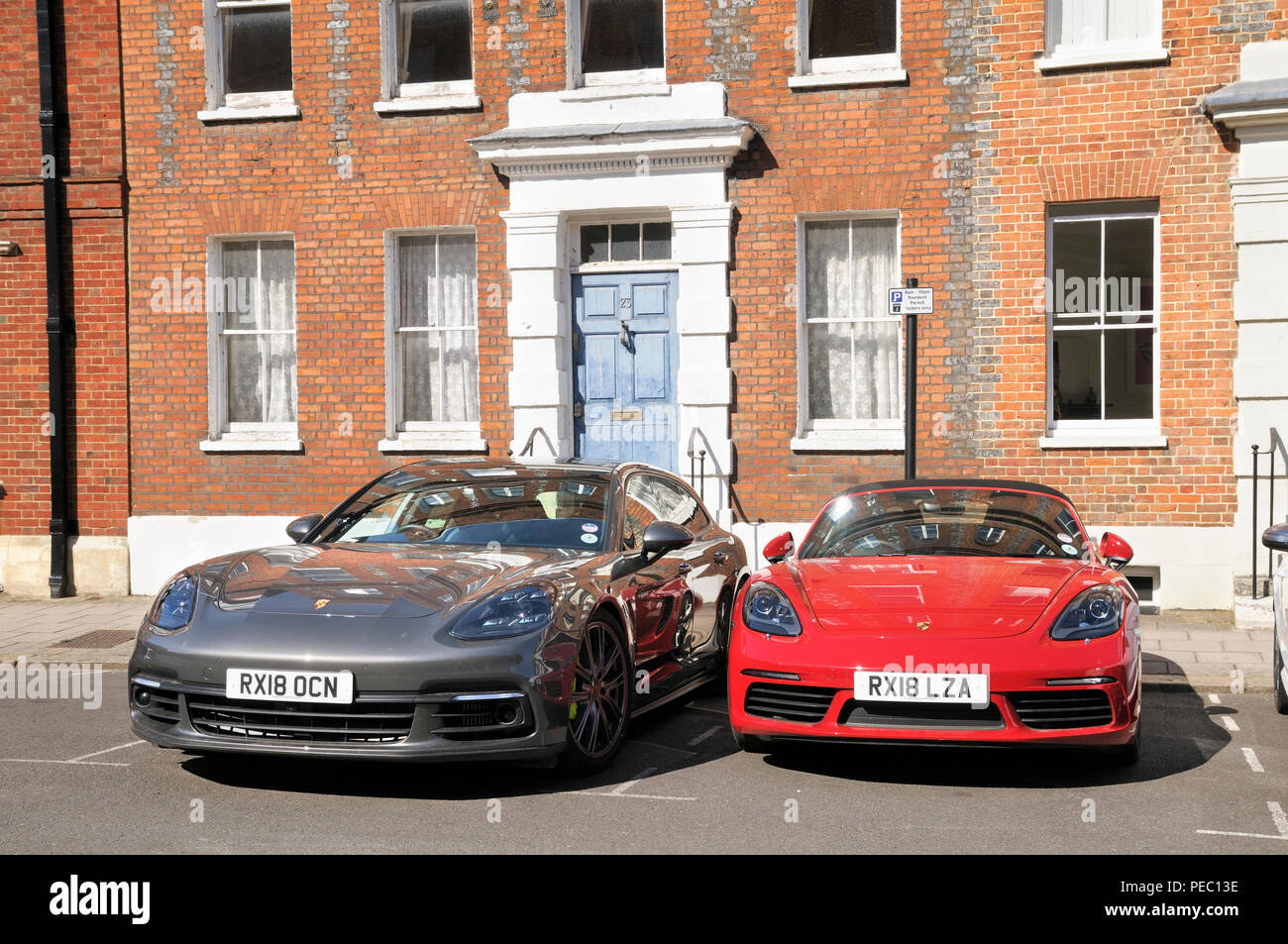 A grey metallic Porsche Panamera 4 and a red Porsche 718 Boxster S parked in front of a Georgian house, Windsor, Berkshire, England, UK Stock Photo
