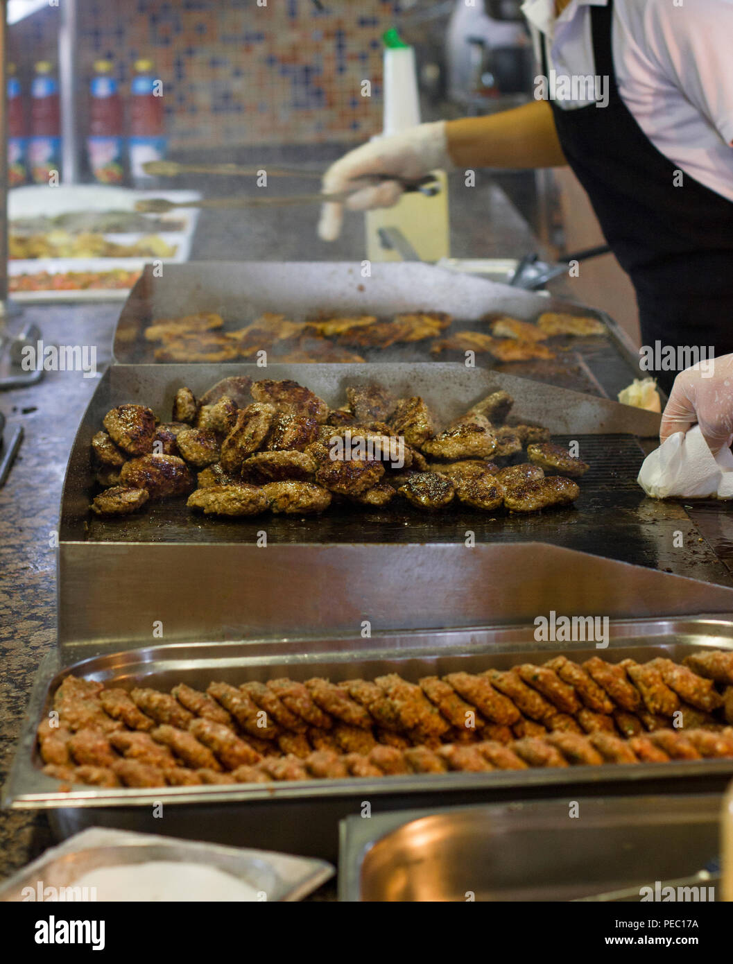 Man fries meat and burger cutlets on a steaming grill Stock Photo