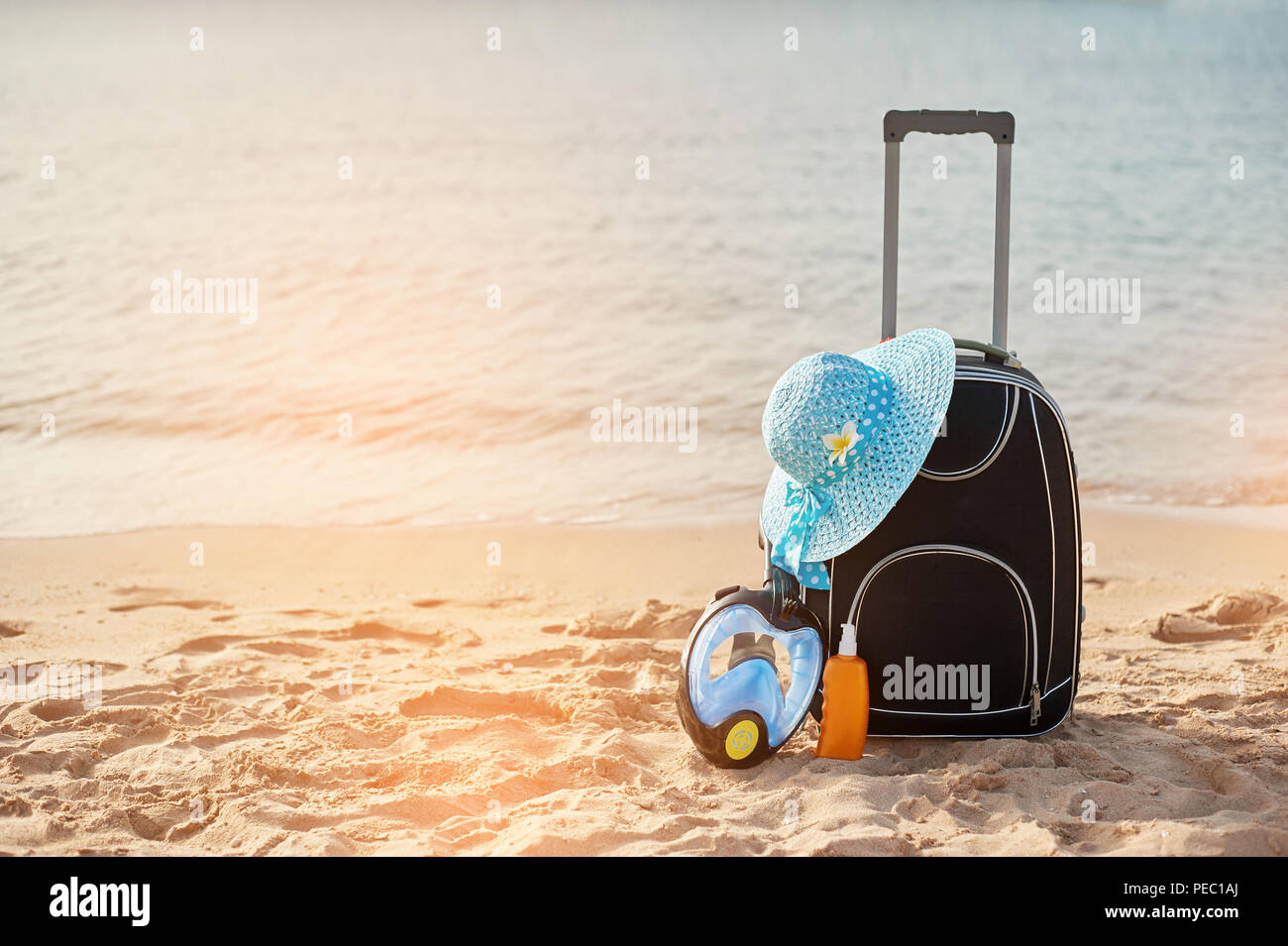 Suitcase and hat, sunscreen with a mask. The tropical sea, beach in the background. The concept of summer recreation travel and cruise traffic Stock Photo