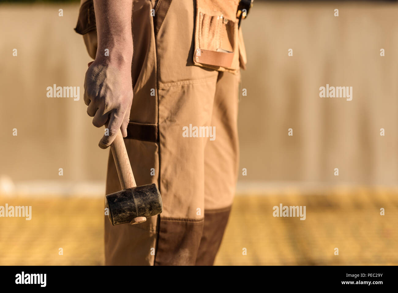 cropped image of construction worker in uniform holding hammer Stock Photo