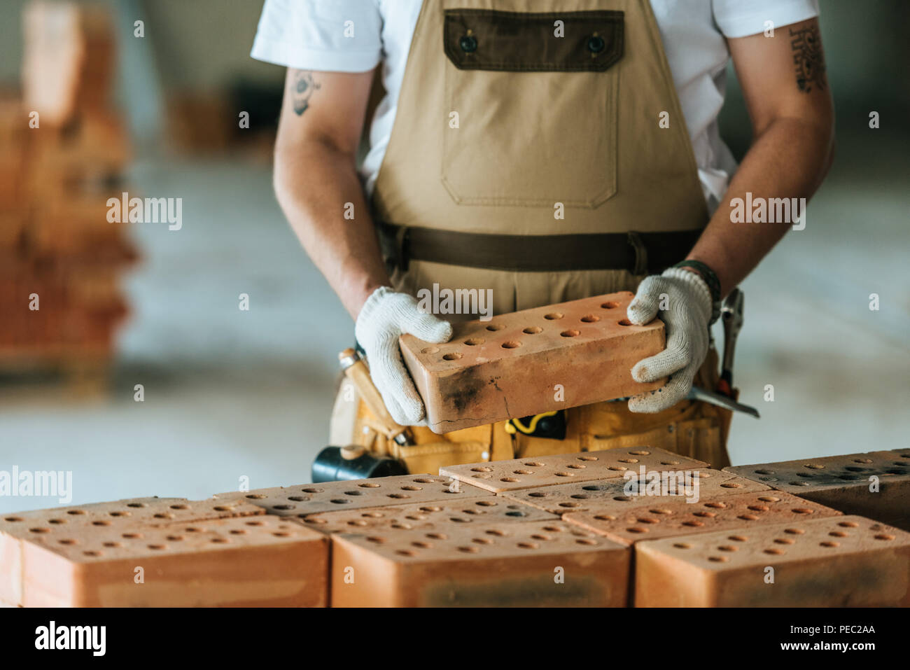 cropped image of construction worker in protective gloves holding brick at construction site Stock Photo