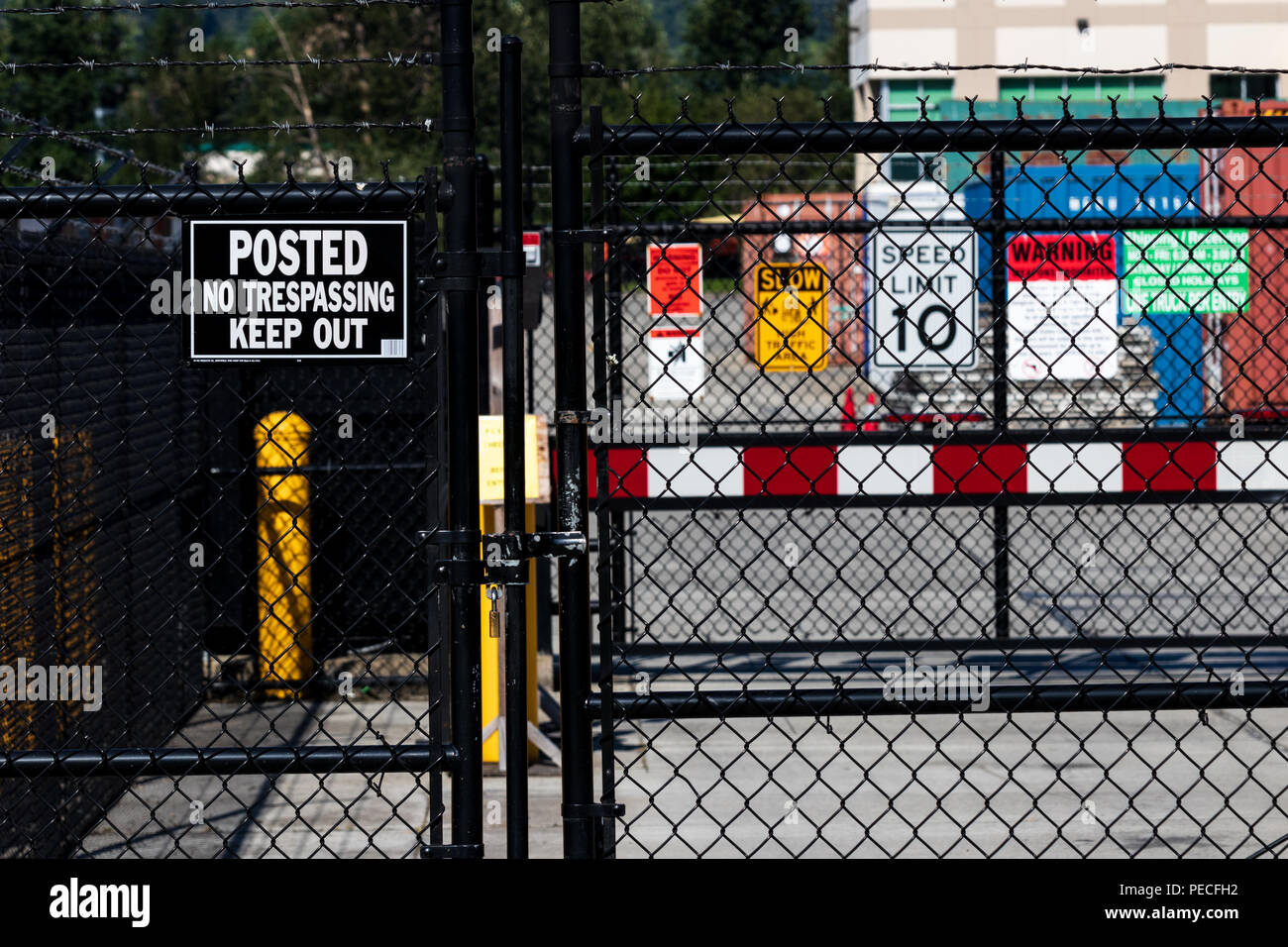 Security gate with various caution and admittance signs with barbed wire Stock Photo
