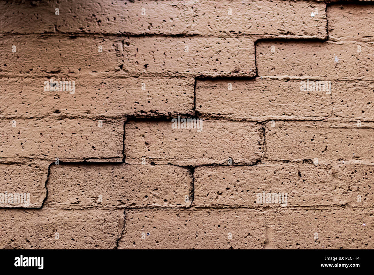 Old faded cracked brick wall in angled light Stock Photo