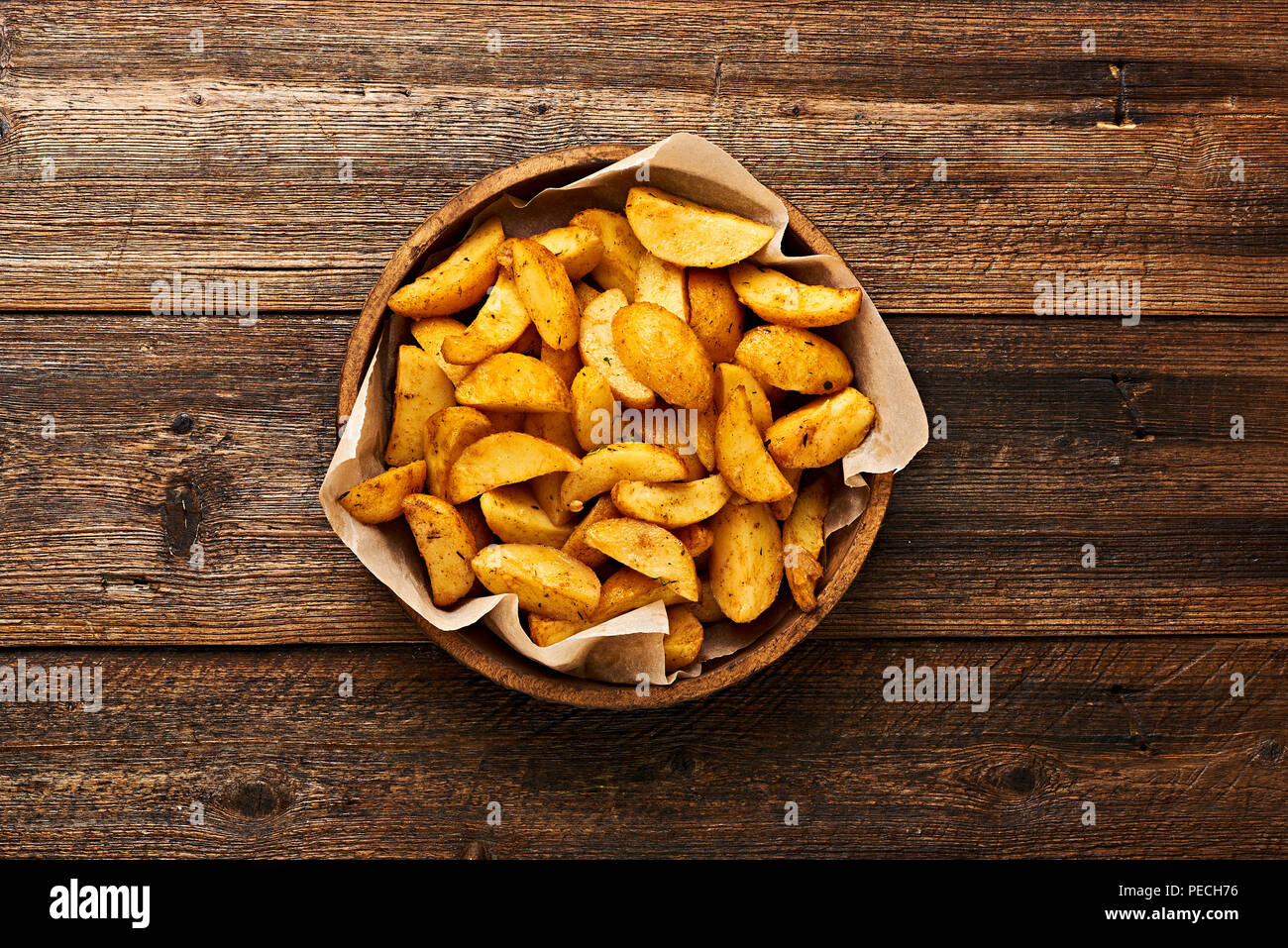 Roasted potato in bowl on wooden table with copy space. Stock Photo
