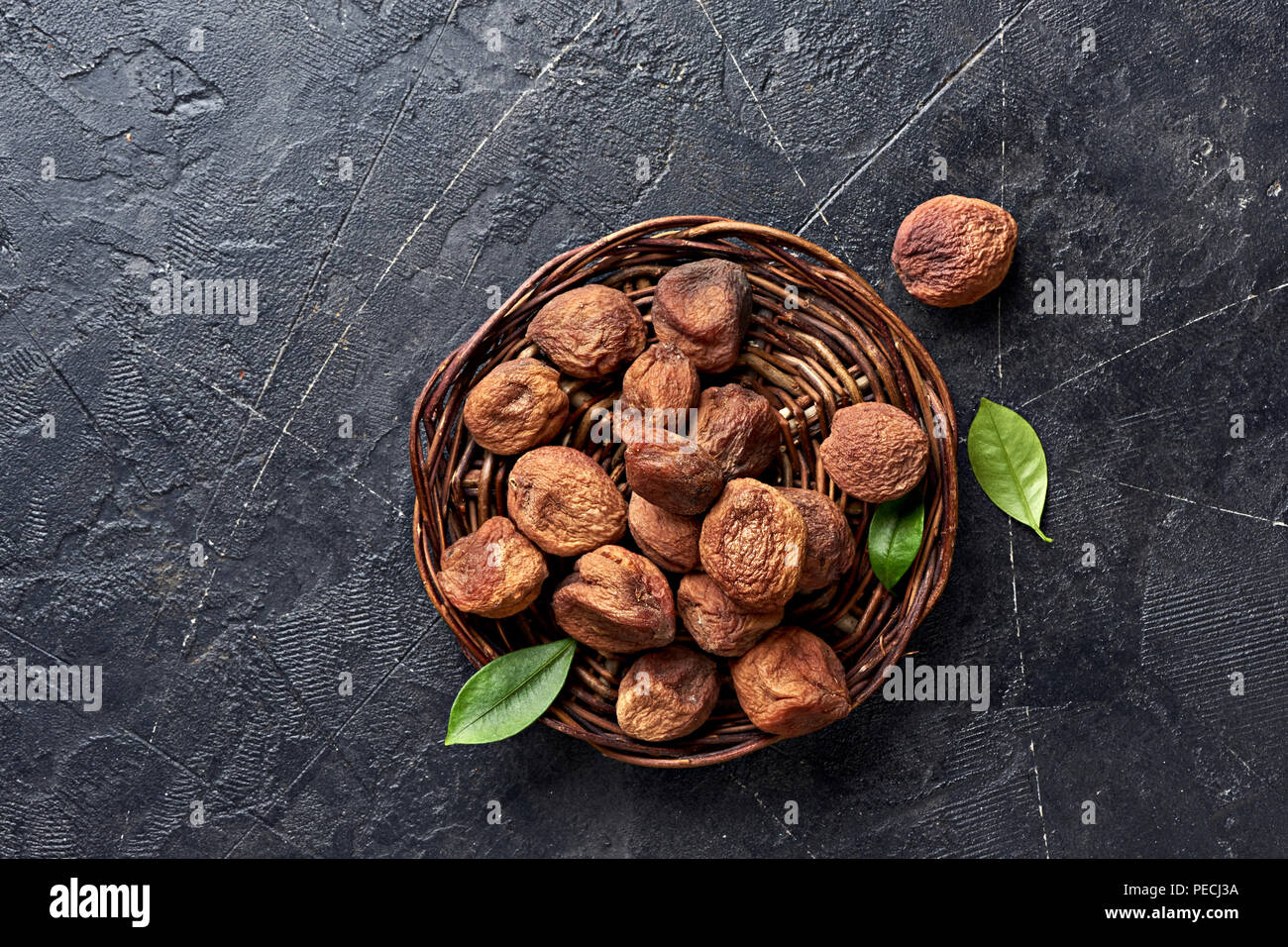 Sun dried apricots on black background. Fruits with green leaves. Top view. Stock Photo