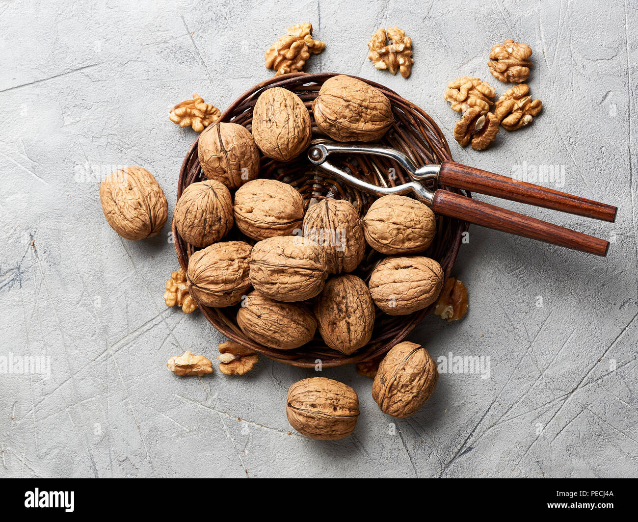 Whole walnuts and kernels on gray background and nutcracker. Stock Photo