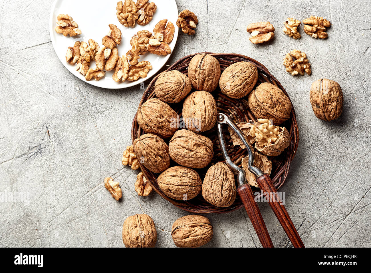 Whole walnuts and kernels on gray background and nutcracker. Stock Photo