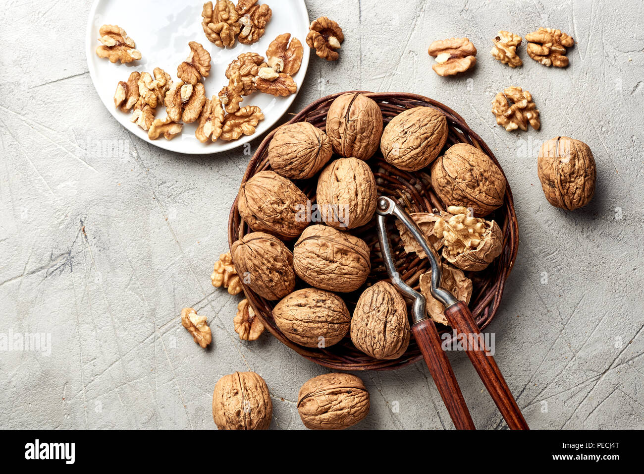 Whole walnuts and kernels on gray background and nutcracker. Stock Photo