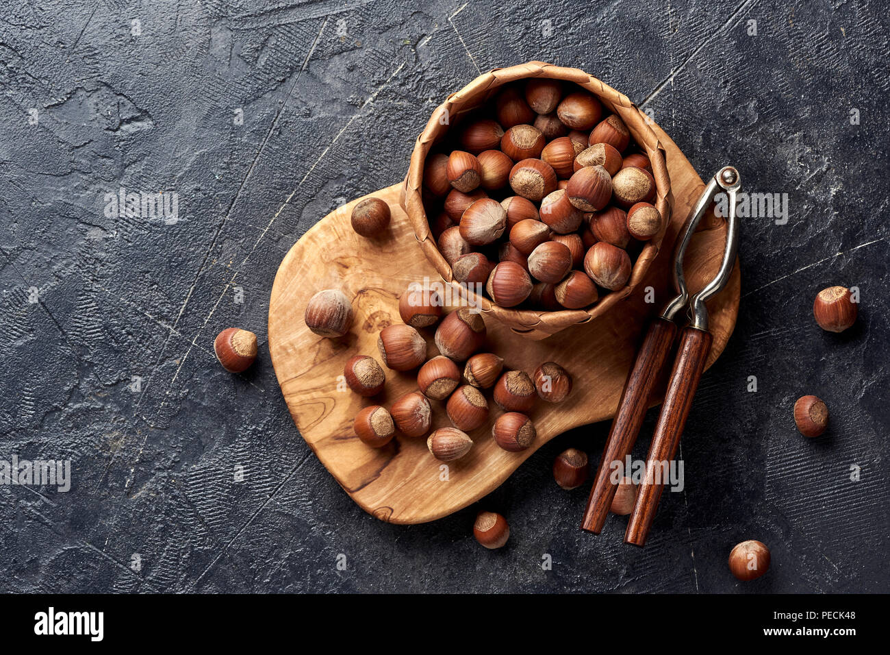 Hazelnut with nutcracker on olive wooden board. Copy space for text. Top view. Stock Photo