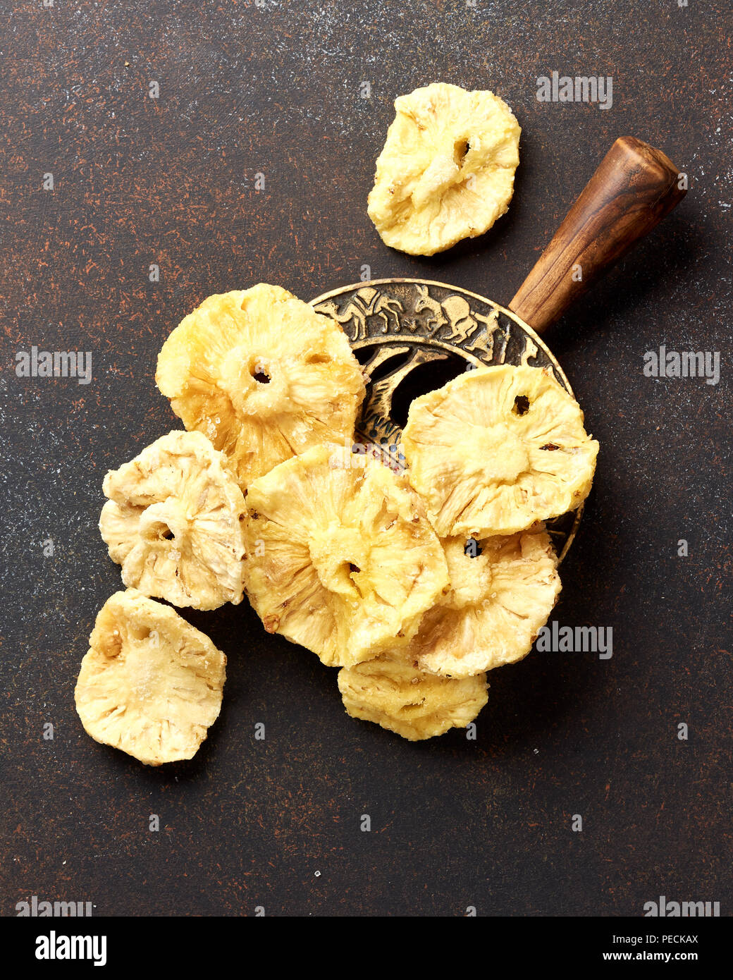 Dried candied pineapple rings. Sliced sweet fruits on brown concrete