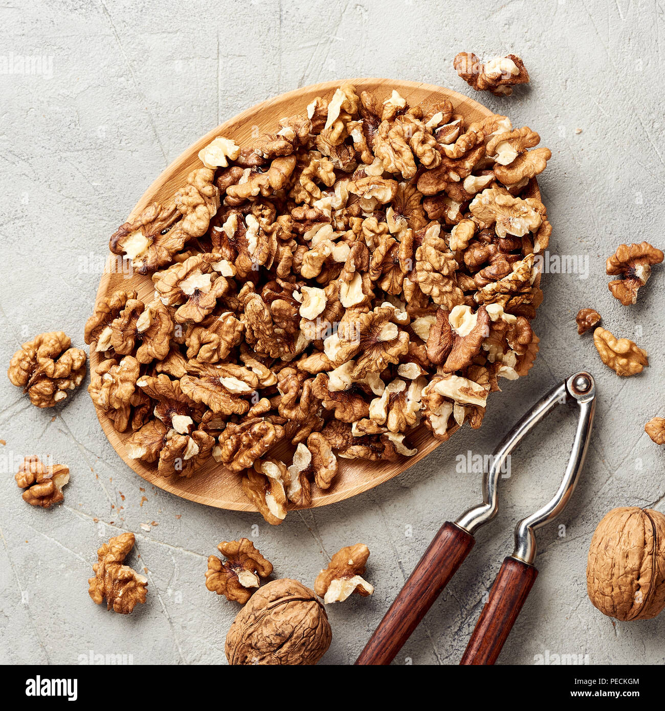 Walnut kernels on gray background and nutcracker. Stock Photo