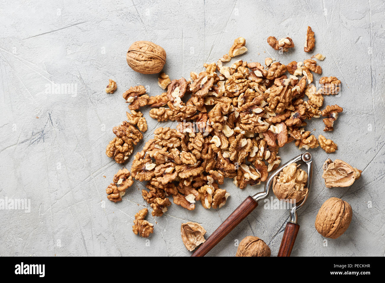 Walnut kernels on gray background and nutcracker. Stock Photo