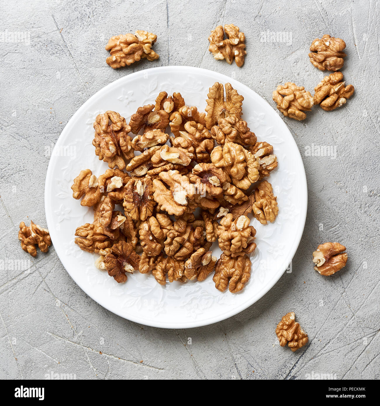 Walnut kernels on white plate over gray background. Stock Photo